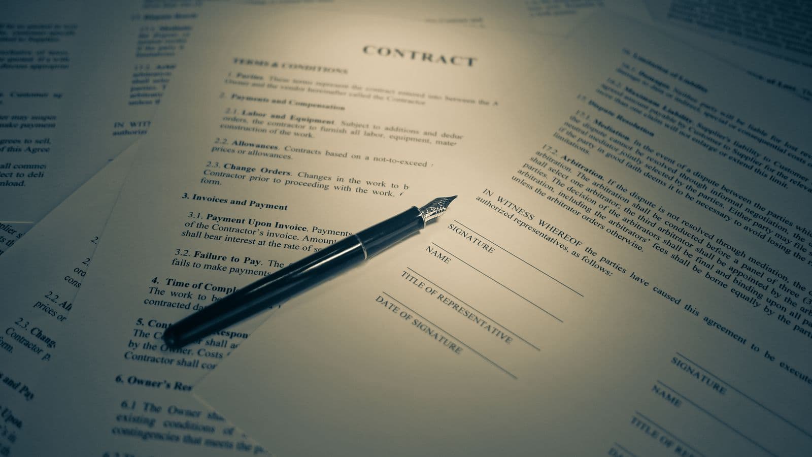 Legal documents and a pen resting on paperwork awaiting signature